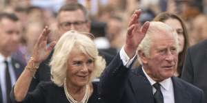 King Charles III,and Camilla,the Queen Consort,wave to the crowd outside Buckingham Palace.