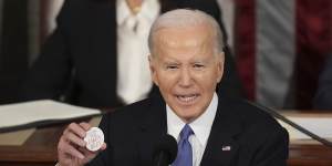 President Joe Biden holds up a Laken Riley button.