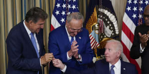 President Joe Biden hands the pen he used to sign the Democrats’ landmark climate change and health care bill to Senator Joe Manchin. Also pictured is Senate Majority Leader Chuck Schumer and Majority Whip James Clyburn.