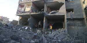 Palestinians stand by a building destroyed in an Israeli airstrike in the Rafah border,Gaza Strip.