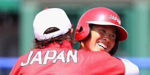 Yamato Fujita of Japan gets a hug from head coach Reika Utsugi after hitting a home run in the fourth inning against Australia during the Tokyo Games.