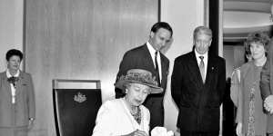 Her Royal Highness Queen Elizabeth II signs the visitors'book at Parliament House,while Prime Minister Paul Keating and Parliament House officials look on,February 1992. 