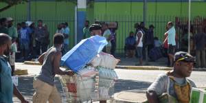 A man pushes a shopping trolley on the street as crowds leave shops with looted goods amid a state of unrest in Port Moresby on Wednesday.