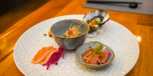 Appetiser plate with raw and cooked slices of wagyu,an oyster with ponzu,lightly cured salmon and a small dish of spinach.