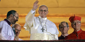 The new pope waves to the crowd from the central balcony of St Peter’s Basilica at the Vatican on March 13,2013. 