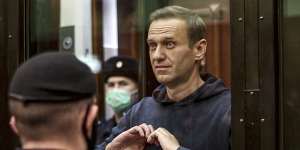 Russian opposition leader Alexei Navalny shows a heart symbol while standing in a cage for defendants in Moscow in 2021. 