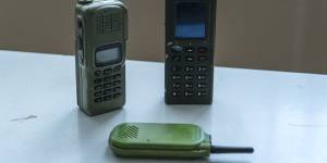 Recovered Russian military radios,standing upright,and a green radio made by Himera,a Ukrainian company that makes $US100 walkie-talkies that can withstand Russian jamming.