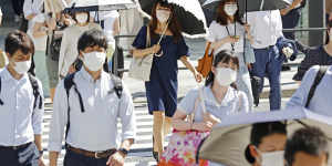 Commuters use parasols to shield themselves from the sun in Tokyo on Monday.