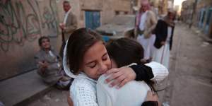 Girls react as they stand near their house which was damaged by a Saudi-led airstrike last Saturday.