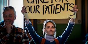 An attendee holds a placard during an emergency public meeting at Fitzroy Town Hall last year about the cohealth closures.