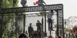 Tunisian soldiers guard the main entrance of the parliament as demonstrators gather outside the the gate in Tunis.