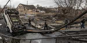 Members of the Ukrainian military walk across a destroyed bridge near the frontline amid fighting in Bucha and Irpin in Ukraine. 