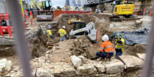 A bulldozer breaking up and removing the significant archaeological remains under Adelaide Street.