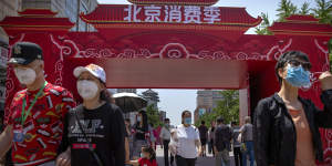 People wearing face masks to protect against the new coronavirus walk at a government event aiming to stimulate consumer demand and consumption in Beijing,Saturday,June 6,2020. 