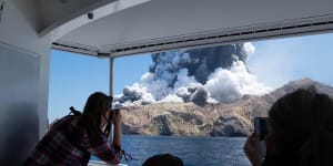 Tourists on a boat look at the eruption of the volcano on White Island,New Zealand,on December 9,2019. 