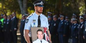 Sergeant Glen Thomas holds a photograph of Senior Constable Brett Forte during the fallen officer’s funeral in Toowoomba on June 7,2017.