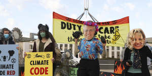 Extinction Rebellion protesters wearing Prime Minister Scott Morrison and Environment Minister Sussan Ley masks out the front of Parliament House.