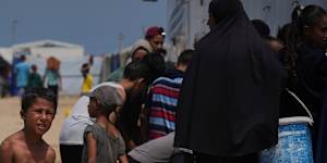 Displaced Palestinians gather to collect water from a truck during a heat wave at a makeshift tent camp in Khan Younis,Gaza Strip on Wednesday.