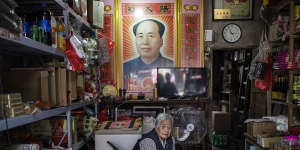 A woman sits in her shop,a poster of Mao hanging behind her,in Hong’an county in June 2021.