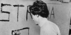 Greg Shackleton painting the word ’Australia” and a flag on the wall of a building in Balibo.