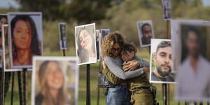 Israelis embrace next to photos of people killed and taken captive by Hamas militants during the attack on the Nova music festival in southern Israel on October 7.