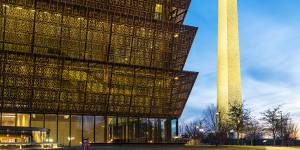 The National Museum of African American History and Culture at night with the Washington Monument in downtown Washington DC.