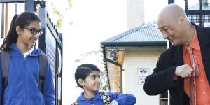 Merrylands East Primary School principal John Goh greets students Maitreyi and brother Yajat Patel at 7.30am.