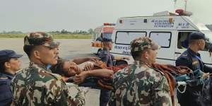 A woman airlifted from an earthquake-affected area is carried on a stretcher in Nepalgunj,Nepal,after daybreak.