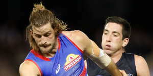 Josh Bruce attempts a kick under pressure from Carlton star Jacob Weitering.