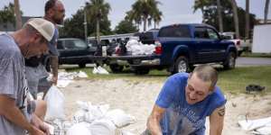 Trenton Spencer (right) fills sandbags for his neighbours in preparation for Hurricane Idalia.