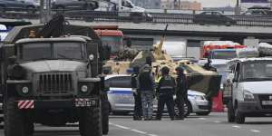 An armoured personnel carrier and police officers stand on the highway on the outskirts of Moscow on Saturday.