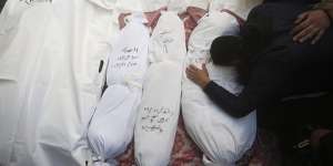 Palestinians mourn relatives killed in the Israeli bombardment of the Gaza Strip outside a morgue in Rafah,on Tuesday. The victims details are written on each wrapped body.