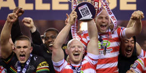 Liam Farrell of Wigan Warriors lift the trophy following victory.