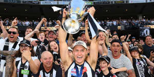 Collingwood captain Darcy Moore brandishes the cup to the Magpie army.