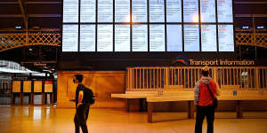 Commuters stand in front of a departures board at Central Station on Monday advising them that all train services are suspended.