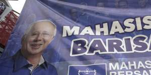 Vehicles pass by a campaign poster of defeated Najib Razak on display along a street in Kuala Lumpur.