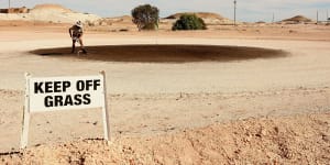 A local rakes out the green at the Coober Pedy Golf Course.