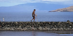Vicente Ruboi walks along a sea wall in Kihei,Hawaii after the fires destroyed part of Maui.