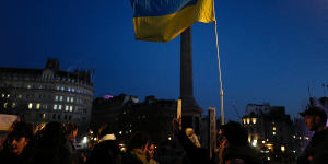 A Ukrainian flag is held high during a protest in Trafalgar Square,London.