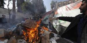 A banner with an image depicting the ousted Syrian president Bashar al-Assad is placed on the fire as a Syrian member of the rebel forces destroys drugs and alcoholic beverages,found at a building,in Damascus.