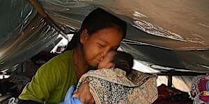 Hong Srey Rith holds her eight-day-old baby,Lin Kakada,in their shelter at the Batthkav primary school. Srey Rith went into labour as she fled her home.