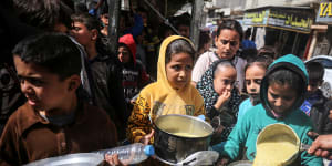 Displaced Palestinians receive cooked food rations in Deir-al-Balah in the central Gaza strip.
