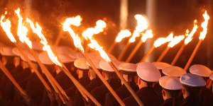Members of the German armed forces carry torches as they march during a military tattoo ceremony,hosted by the Bundeswehr,for outgoing German Chancellor Angela Merkel.
