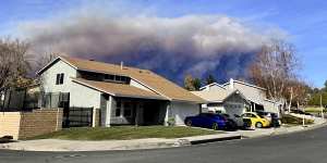 A large plume of smoke caused by the Hughes Fire rises from Castaic Lake as seen from a neighborhood of Santa Clarita,California.