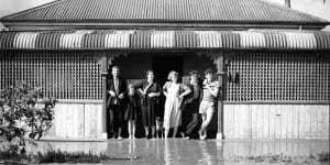 A family stands at the doorway of the doorway of its flooded home in Maitland,NSW,8 August 1952.