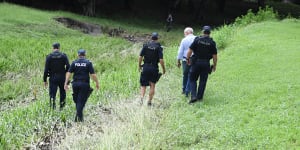 Police search the scene where two bodies were found in a drain running behind the Aitkenvale Library in Townsville. 