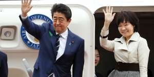 Shinzo Abe waves with his wife Akie Abe while boarding a plane heading for the US in 2018.