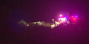 One person is dead and at least two others are fighting for life after a bus rollover in north Queensland injured about 20 people.