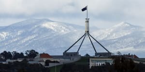 Parliament House in Canberra with snow on the mountains behind on June 1.