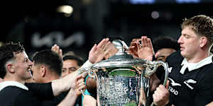 The All Blacks lift the Bledisloe Cup after their victory over the Wallabies.